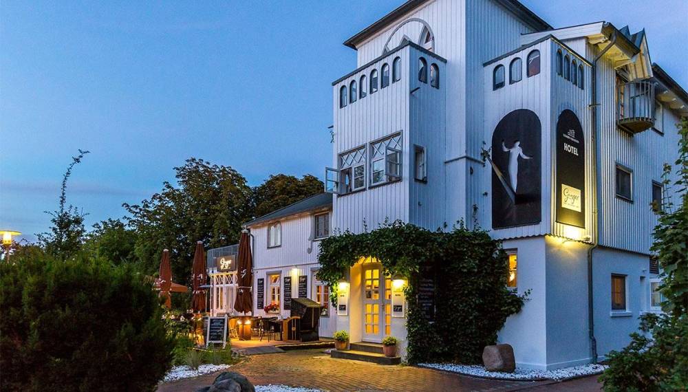 Außenansicht des Hotel Elisabeth von Eicken bei Abenddämmerung mit Terrasse und Cafébereich.