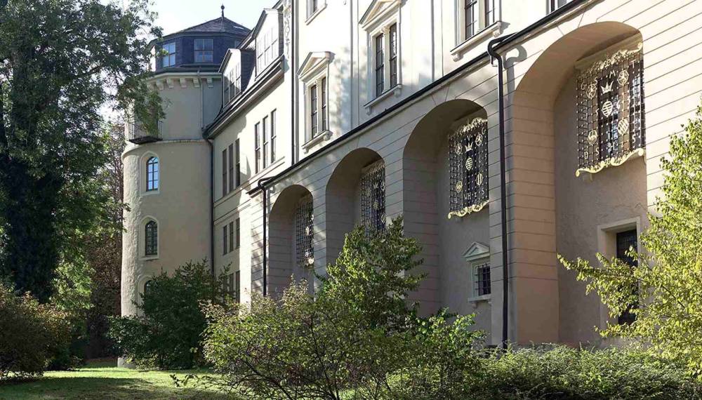 Herzogin Anna Amalia Bibliothek in Weimar mit historischem Gebäudetrakt, Rundturm und Arkaden im grünen Innenhof.
