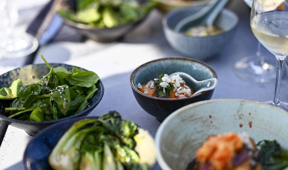 A selection of fresh vegetarian dishes arranged in bowls, with green leafy vegetables and tempting details.