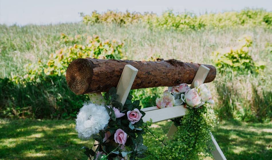 Geschmückter Hochzeitsstamm mit Blumen und grüner Dekoration für traditionelle Zeremonien an der Ostsee.