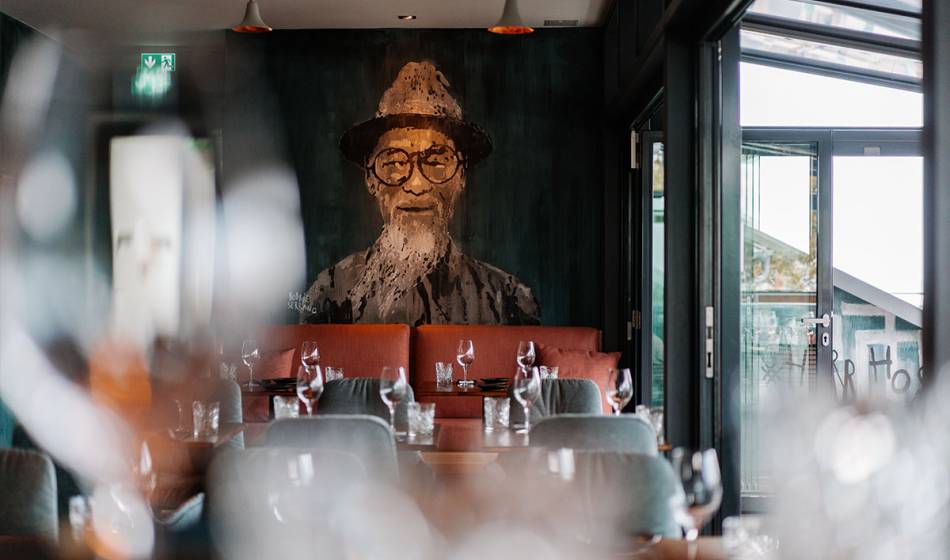 Interior of the #herrhoshi in the Hotel Seezeichen with comfortable seating, set tables and a large mural.