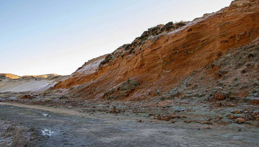 Steilküste des Morsum-Kliffs auf Sylt mit rotbraunen Erdschichten und einem naturbelassenen Pfad im Vordergrund.