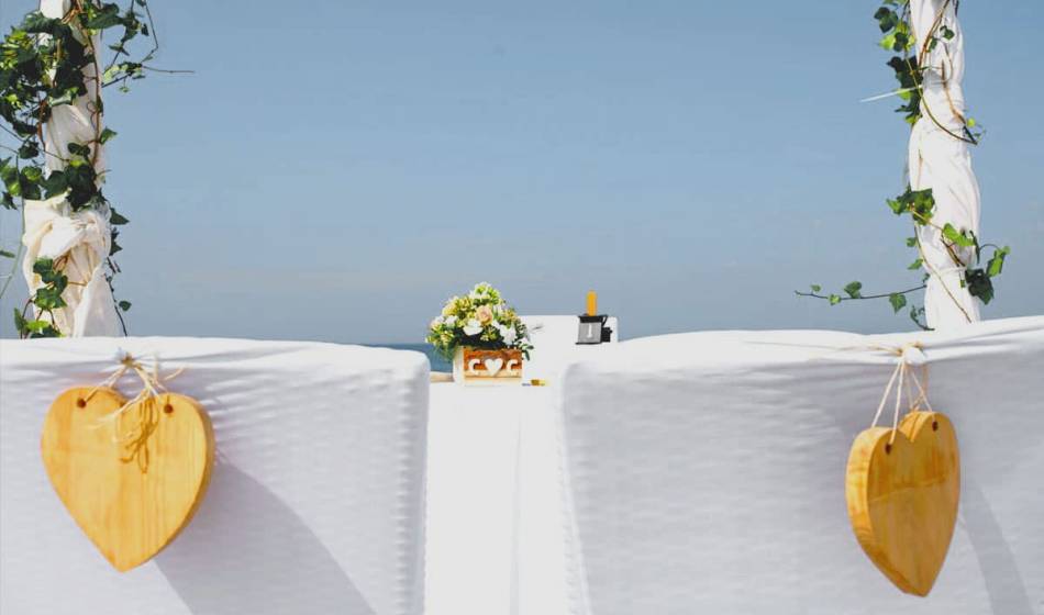 Zwei dekorierte Stühle mit Holzherzen und Blumenschmuck für eine Strandtrauung im Hotel Künstlerquartier Seezeichen.