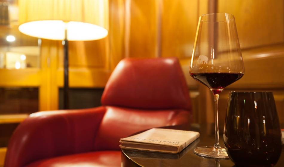 Cosy armchair with red wine and a book in the Hotel Elephant Weimar library