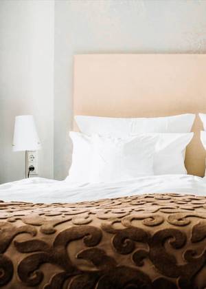Hotelzimmer im Künstlerquartier Seezeichen in Ahrenshoop mit großem, gemütlichem Doppelbett und stilvollem Interieur.