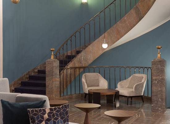 Moderne Lobby mit geschwungener Treppe, stilvollen Sesseln und elegantem Dekor im Elephant Hotel Weimar.