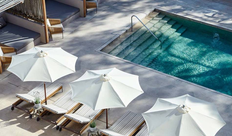 Moderner Poolbereich mit schattigen Liegen und großen weißen Sonnenschirmen im Barefoot Hotel Mallorca.