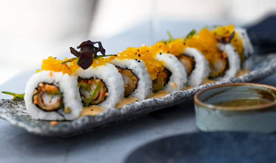 Nahaufnahme von American Sushi-Rollen, gefüllt mit Tempura und Gemüse, dekoriert mit Fischrogen und Kräutern im #herrhoshi.