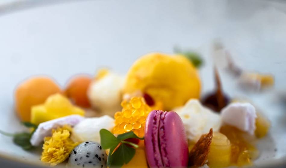 Dessert mit bunten Früchten, Macaron, essbaren Blüten und kleinen Cremehäubchen, dekorativ angerichtet im #herhoshi.