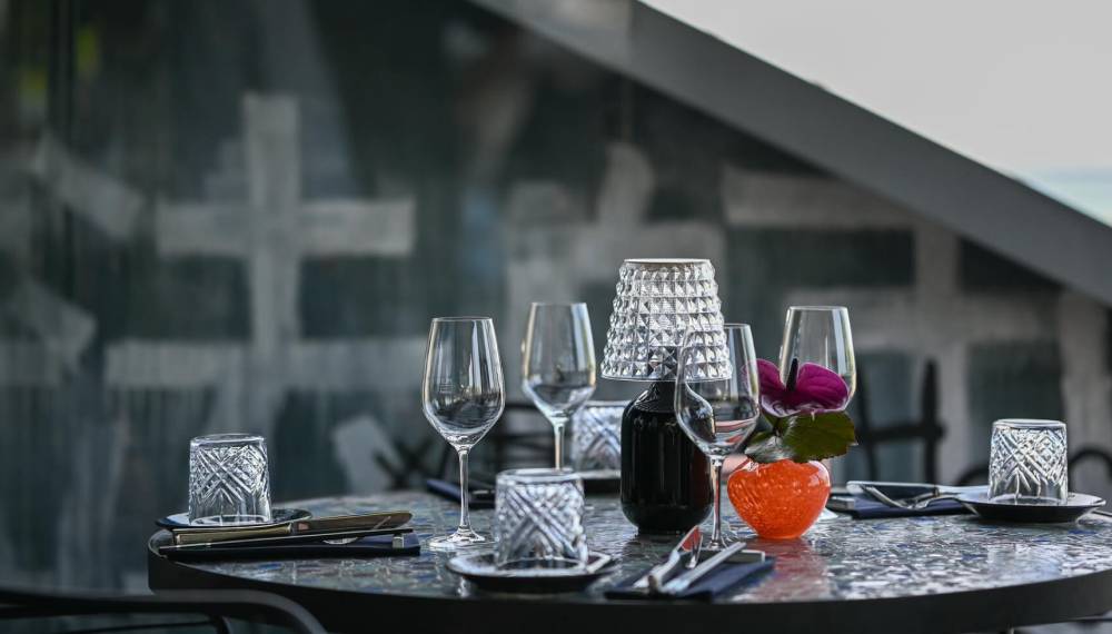 Ein stilvoll gedeckter Tisch mit mehreren Gläsern und einer orangenen Vase in der Mitte.