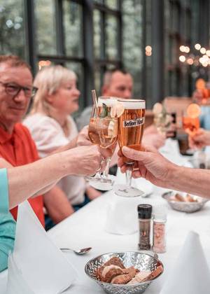 Menschen stoßen beim Essen im Gasthaus Zur historischen Mühle an.