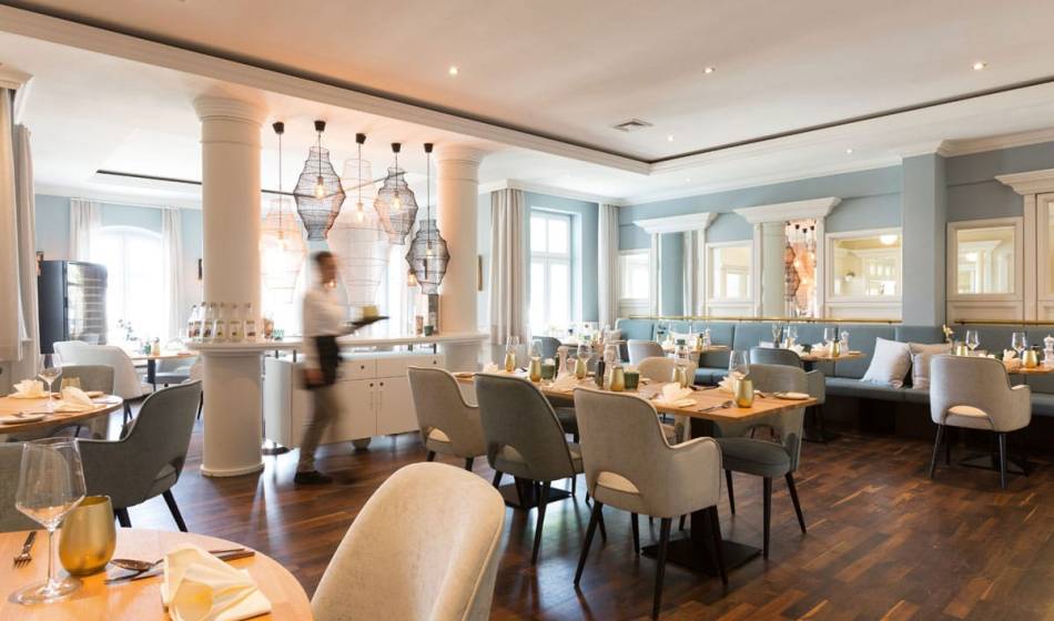 Bright and elegant coastal silver restaurant in the Vju Hotel Rügen with set tables and a luxurious ambience.