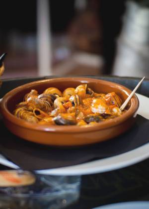 Nahaufnahme von mallorquinischen Tapas-Schnecken in würziger Tomatensoße in einer Tonpfanne
