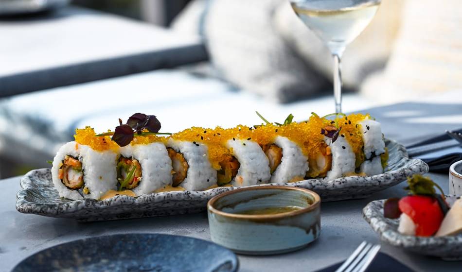 Sushi rolls with caviar and vegetable filling, decoratively arranged on a platter, accompanied by a glass of white wine in #herrhoshi.