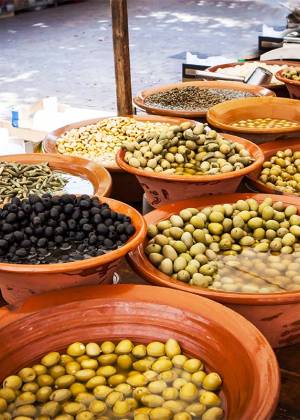 Marktstand mit verschiedenen Oliven und eingelegten Spezialitäten in Tonschalen auf einem Markt auf Mallorca.