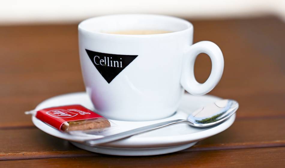 Weiße Cellini-Espressotasse mit Löffel und Keks auf einer Untertasse, auf Holztisch im Café #fraukorn.
