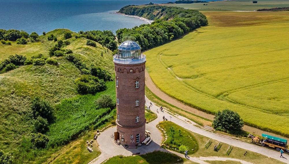 Backsteinturm mit Glaskuppel am Kap Arkona, umgeben von Feldern und Steilküste