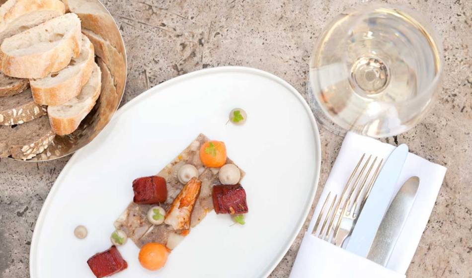 Kreativ angerichtetes Fischgericht mit Beilagen, serviert mit Brot und Weißwein im Hotel Elephant Weimar.