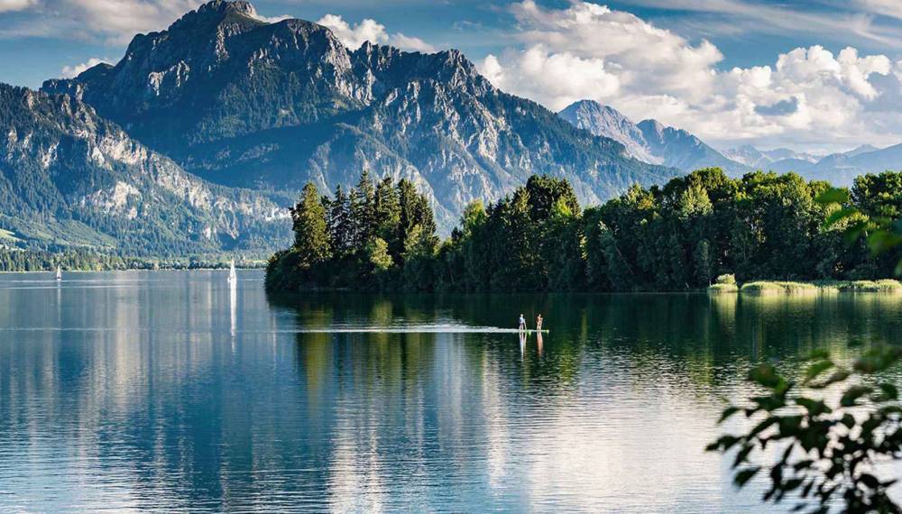 Bergsee mit Alpenpanorama im Allgäu mit Blick auf bewaldete Ufer und hohe Gipfel.