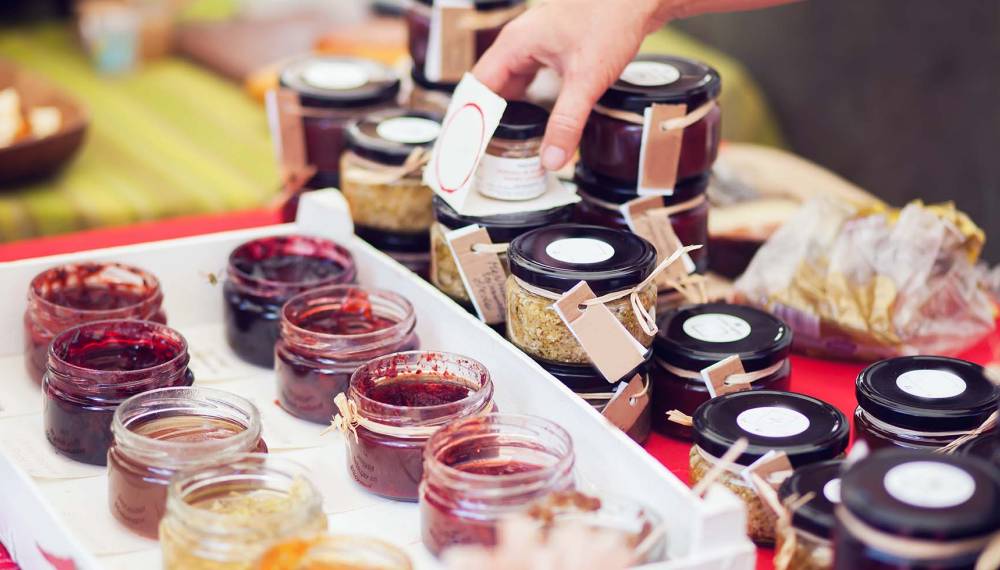 Selbstgemachte Marmeladen in kleinen Gläsern an einem Marktstand, ein beliebtes Mitbringsel von Rügen.