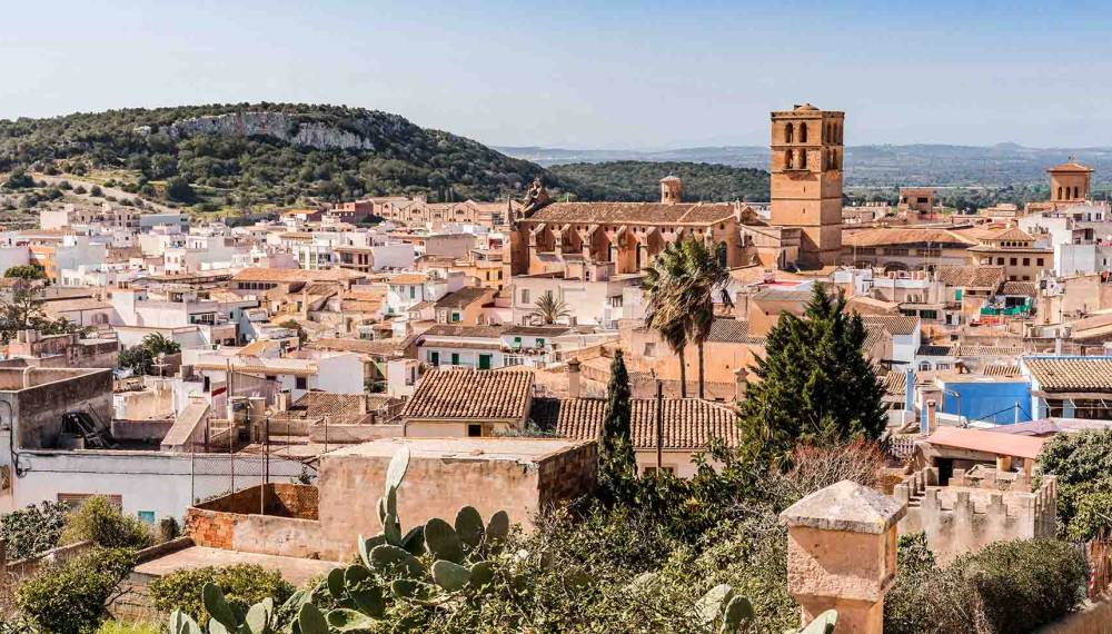 Blick über die Dächer der Stadt Felanitx auf Mallorca mit der Kirche Sant Miquel und Hügeln im Hintergrund.