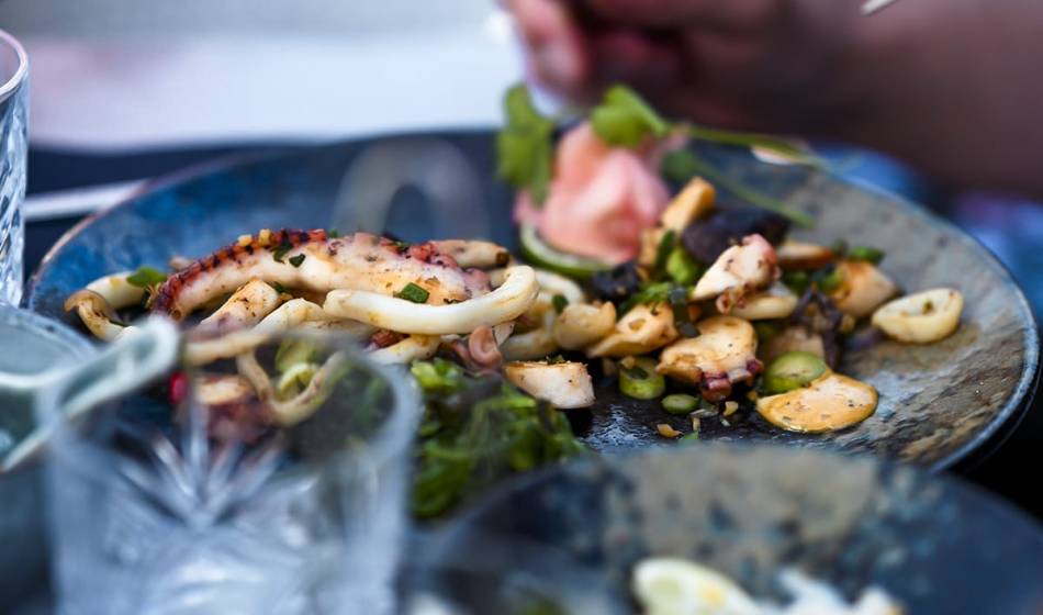 Teller mit gegrillten Meeresfrüchten, darunter Tintenfisch und Muscheln, dekoriert mit Kräutern und Gemüse im Restaurant #herrhoshi.