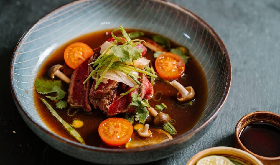 A bowl of strong broth, beef, mushrooms, tomatoes and fresh herbs, artfully arranged in #herrhoshi.