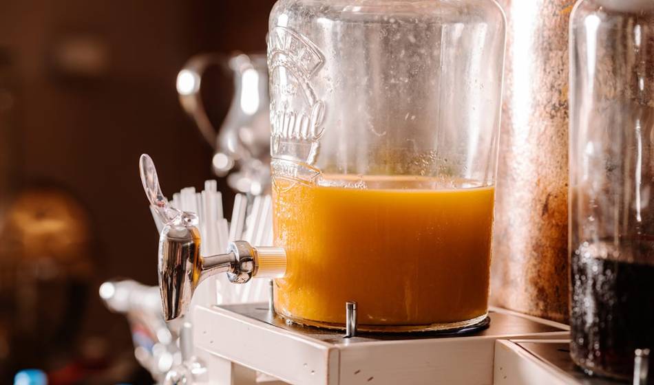 Glaskaraffe mit frischem Orangensaft und Zapfhahn im Frühstücksbereich des #fraukorn im Künstlerquartier Seezeichen.