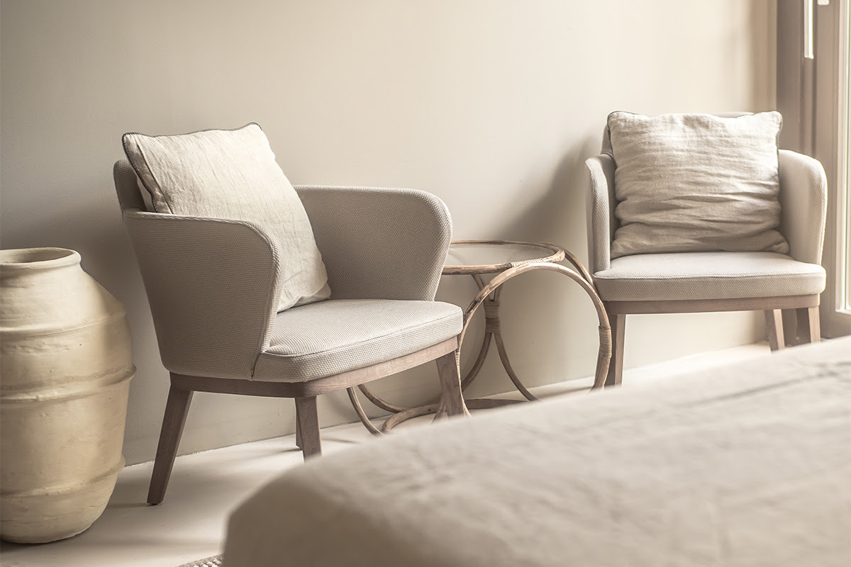 Gemütliche Sitzecke mit zwei Sesseln, Kissen und Beistelltisch in der Pequeña Suite des Barefoot Hotels Mallorca.