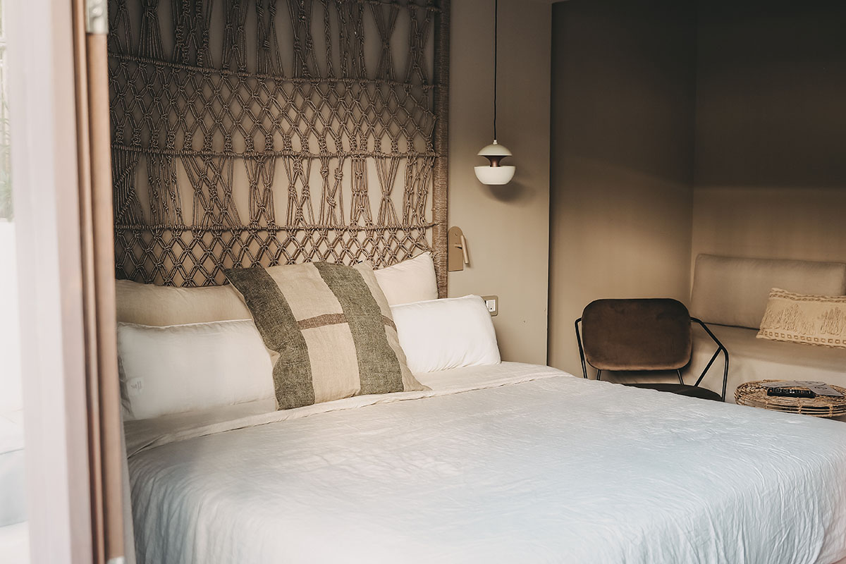 Gemütlicher Schlafbereich im Zimmer Pueblo des Barefoot Hotel Mallorca mit dekorativem Kopfteil und Kissen.