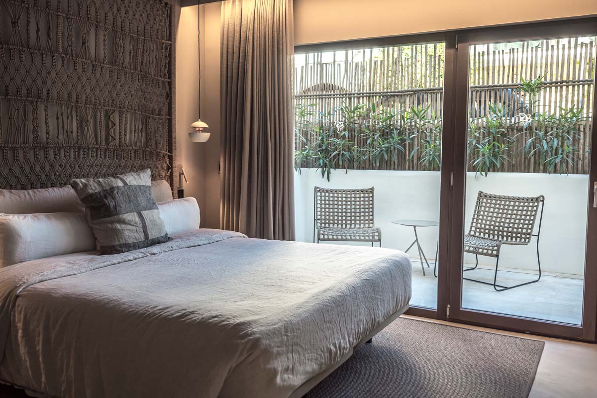 Modernes Pueblo-Zimmer des Barefoot Hotel Mallorca mit Doppelbett, großen Fenstern und Zugang zur privaten Terrasse.