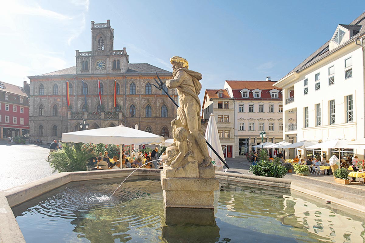 Historischer Brunnen auf Weimars Marktplatz mit umliegenden Cafés und Rathaus