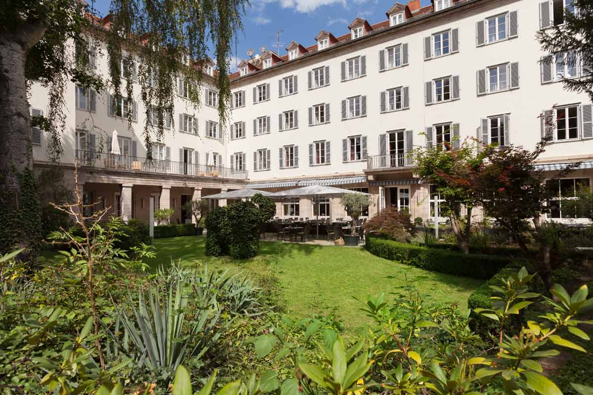 Außenansicht des Hotel Elephant Weimar mit Blick auf den gepflegten Garten und die eleganten Fenster des Gebäudes.