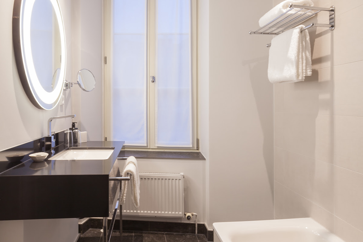 Helles Badezimmer mit großzügigem Waschbecken und beleuchtetem Spiegel in der Executive Suite im Hotel Elephant.