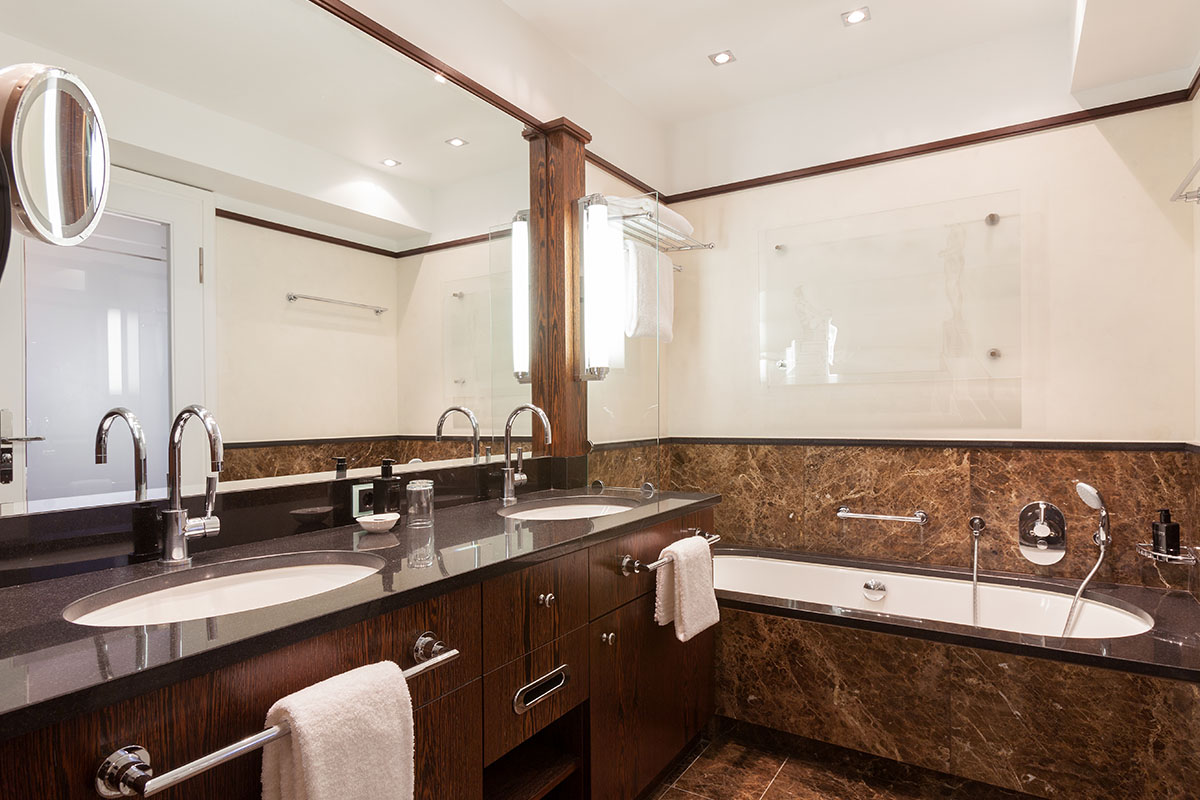 Badezimmer der Thomas-Mann-Suite im Hotel Elephant Weimar mit Doppelwaschbecken, luxuriöser Badewanne und stilvollen Holzdetails.