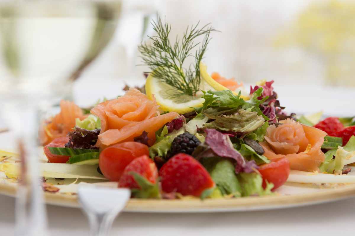 Plate of fresh salmon, berries and salad, lovingly arranged in the Palmengarten of the Hotel Kaiserhof Heringsdorf.