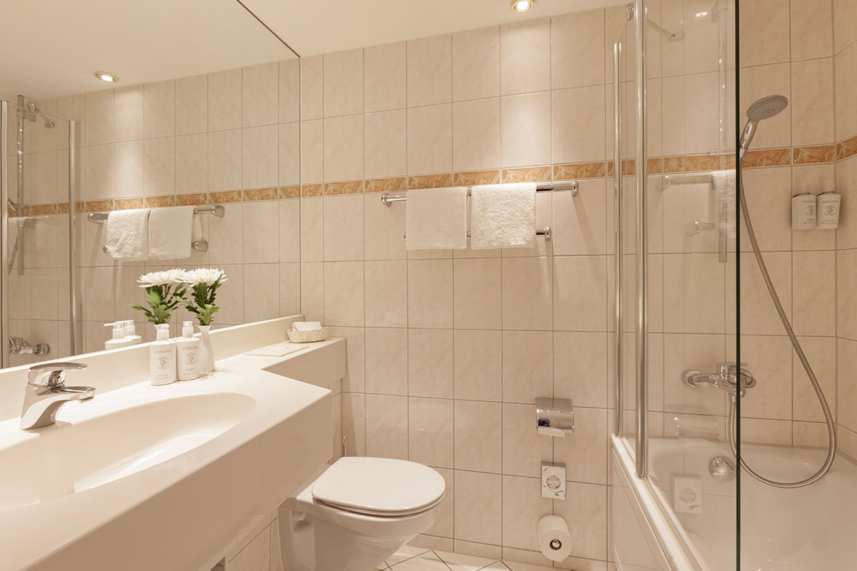 Modern eingerichtetes Badezimmer mit Glasdusche, großzügigem Waschtisch und eleganten Pflegeprodukten im Hotel Kaiserhof.