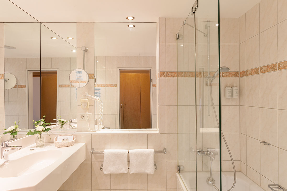 Geräumiges Badezimmer mit Spiegelwand, Dusche und hochwertigen Pflegeprodukten im Comfort-Doppelzimmer im Hotel Kaiserhof.