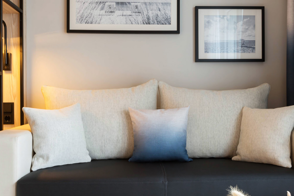 Ein gemütliches Sofa mit mehreren Kissen im Deluxe Doppelzimmer mit Promenadenblick im Hotel Kaiserhof Heringsdorf.