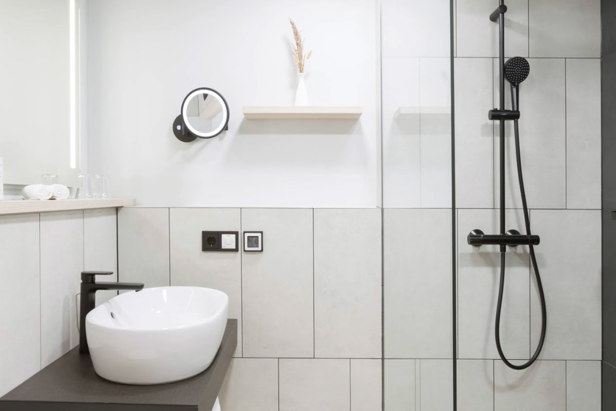 Elegantes Badezimmer in einem Doppelzimmer im Hotel Kaiserhof Heringsdorf mit hellen Fliesen und hochwertiger Ausstattung.