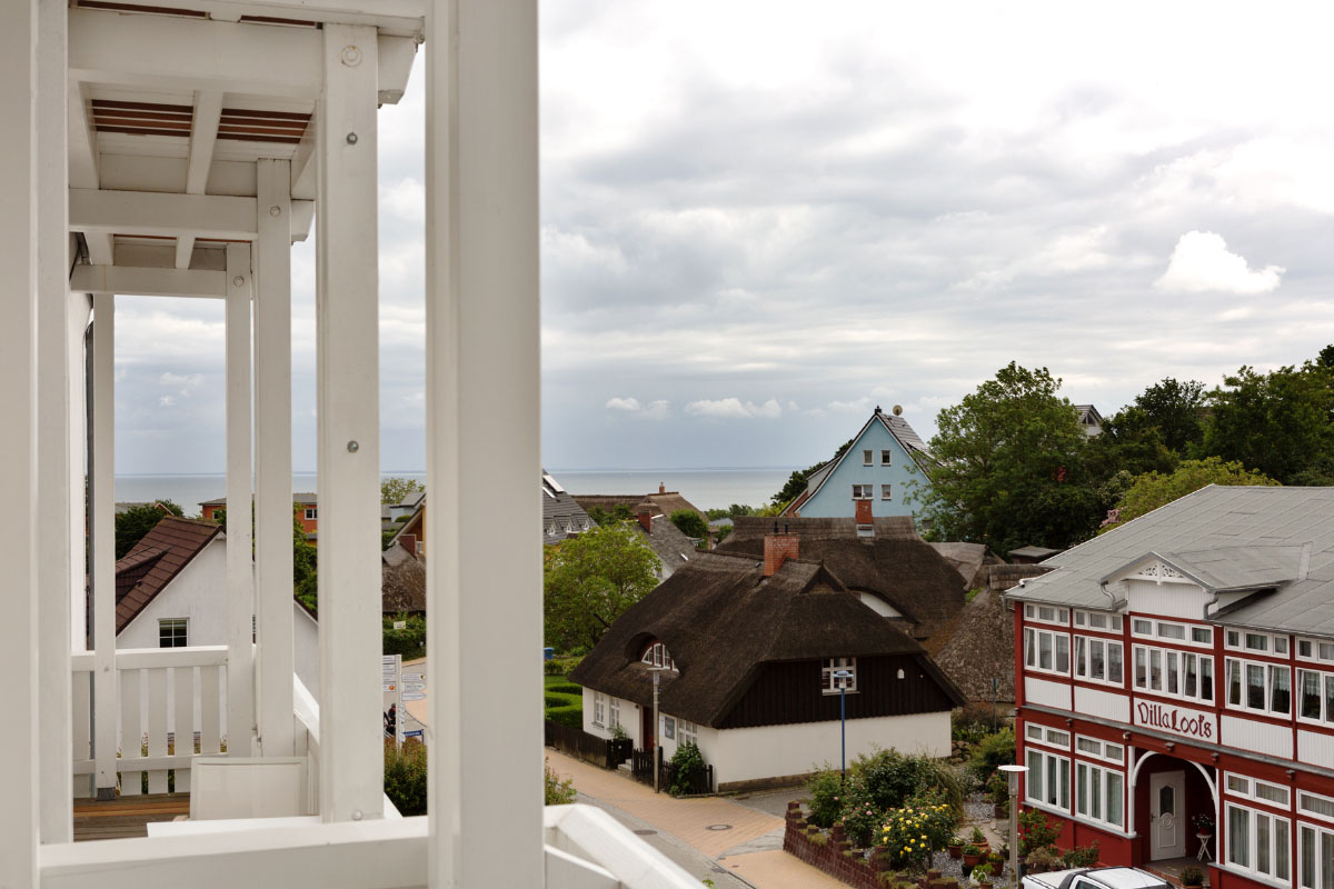 Balkon eines Doppelzimmers im Koopmanns Hotel mit Blick auf traditionelle Häuser und der Ostsee im Hintergrund.