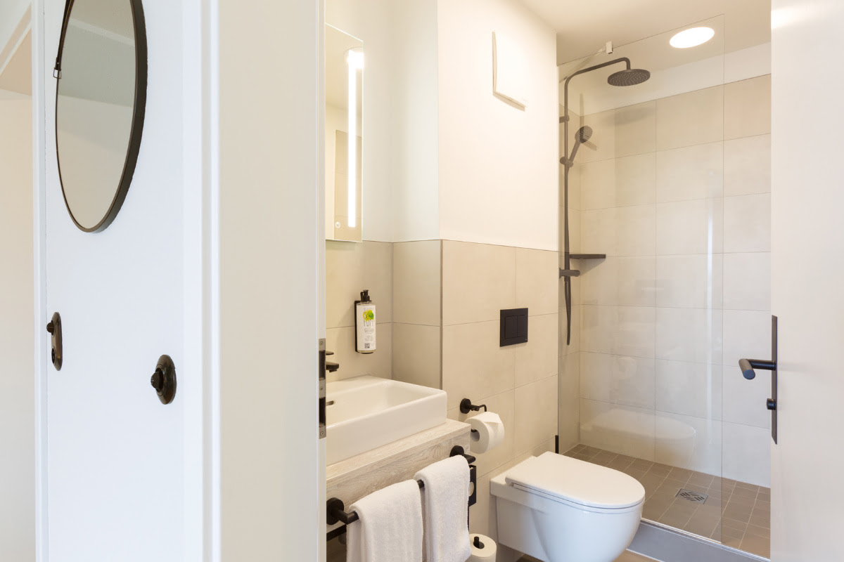 Modernes Badezimmer mit Regendusche, Waschbecken, Spiegel und WC im Komfort-Doppelzimmer im Koopmanns Hotel.