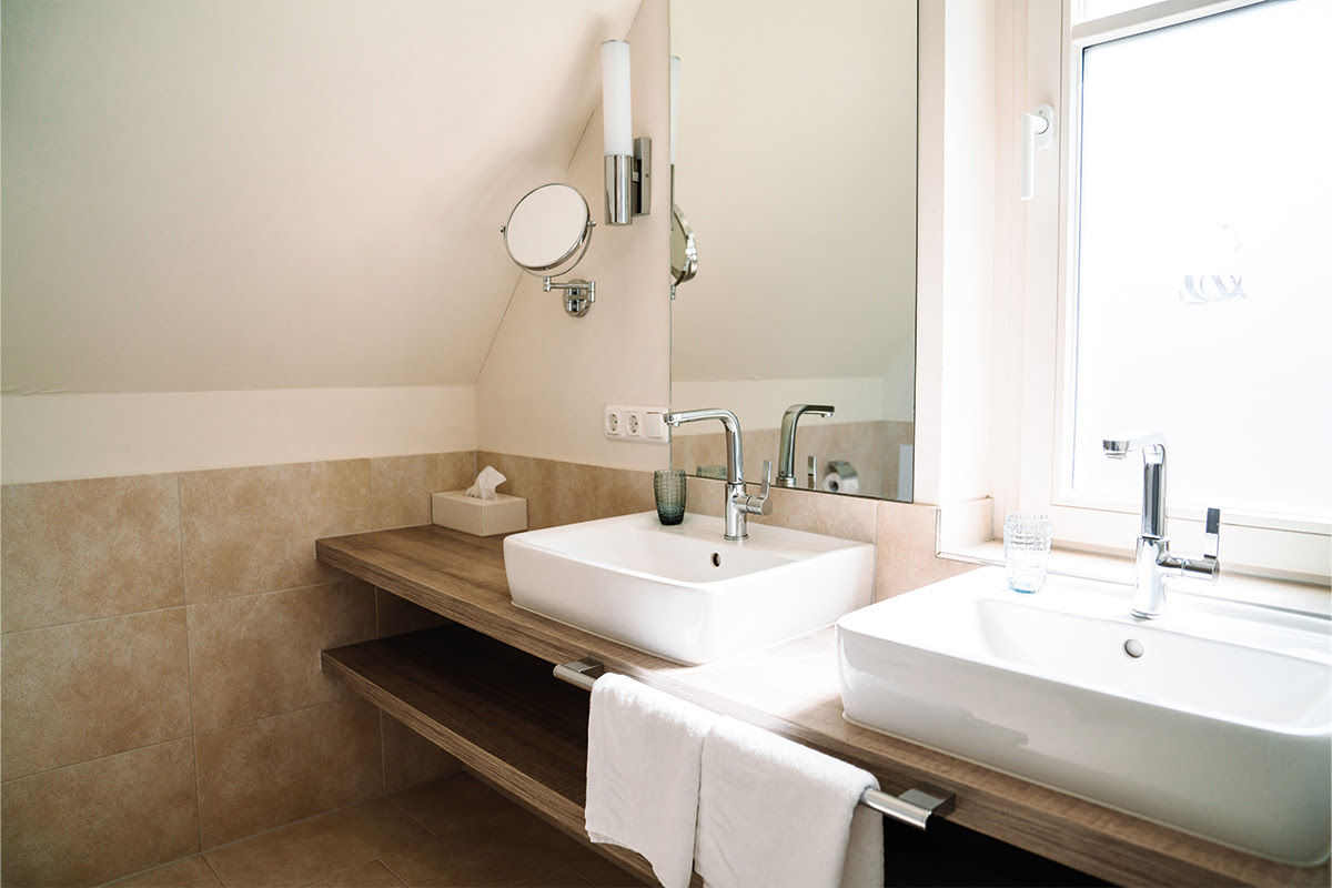 Modernes Badezimmer mit zwei Waschbecken und Tageslicht in der Ferienwohnung Dünenpark im Hotel Künstlerquartier Seezeichen.