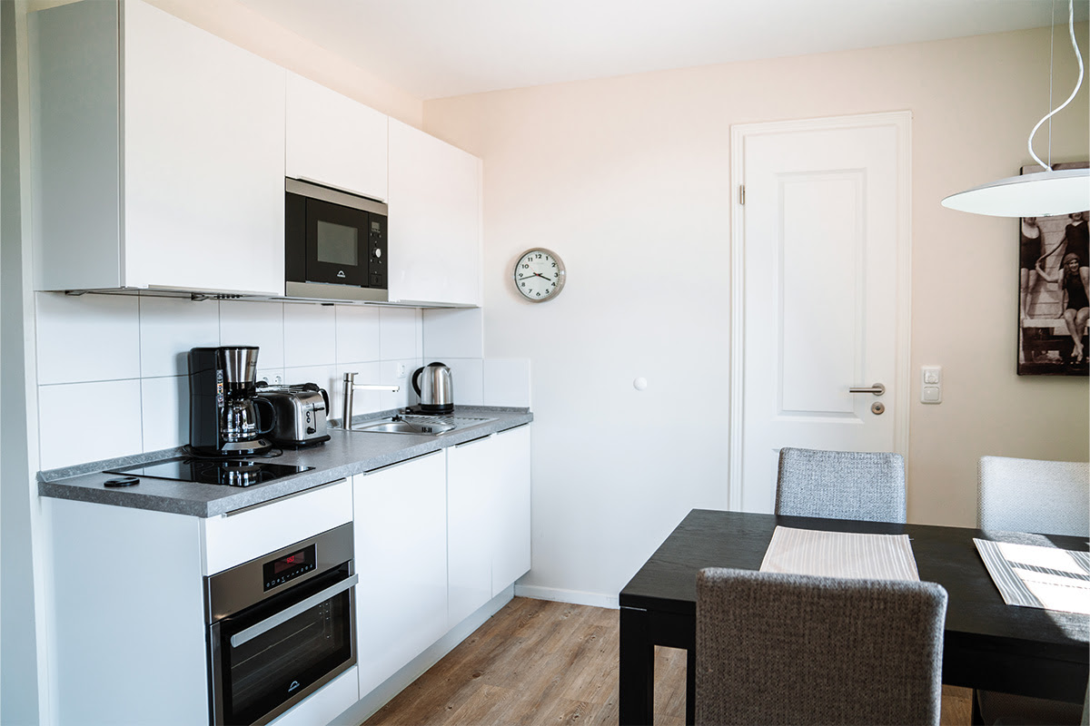Fully equipped kitchenette in the Dünenpark vacation apartment at the Hotel Künstlerquartier Seezeichen with dining area and lake view.