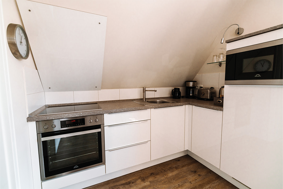 Modern kitchenette in the Seepferd vacation apartment in the Dünenpark in Ahrenshoop with stove, microwave and coffee machine.