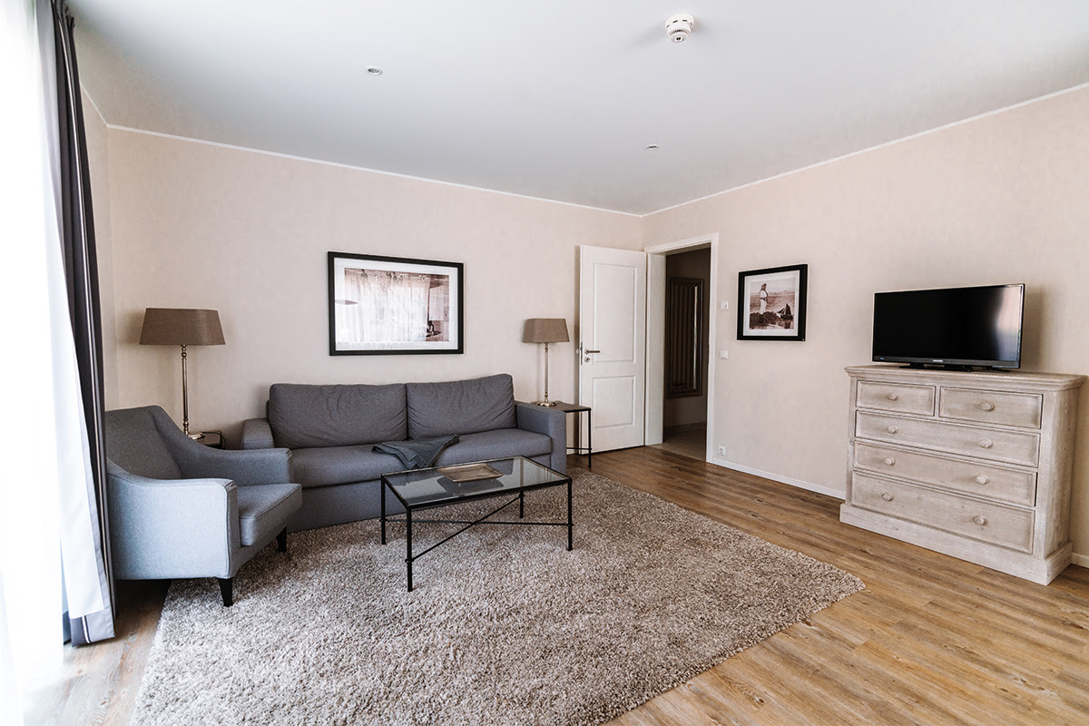 Light-flooded living room with comfortable seating in the Stranddistel vacation apartment in the dune park in Ahrenshoop.