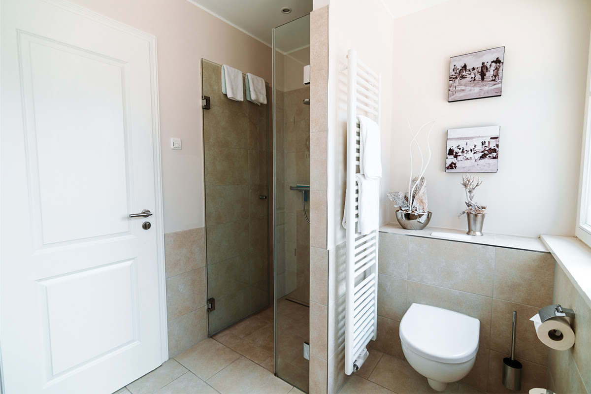 Helles Badezimmer mit Glasdusche in der Ferienwohnung Strandmuschel im Hotel Künstlerquartier Seezeichen.