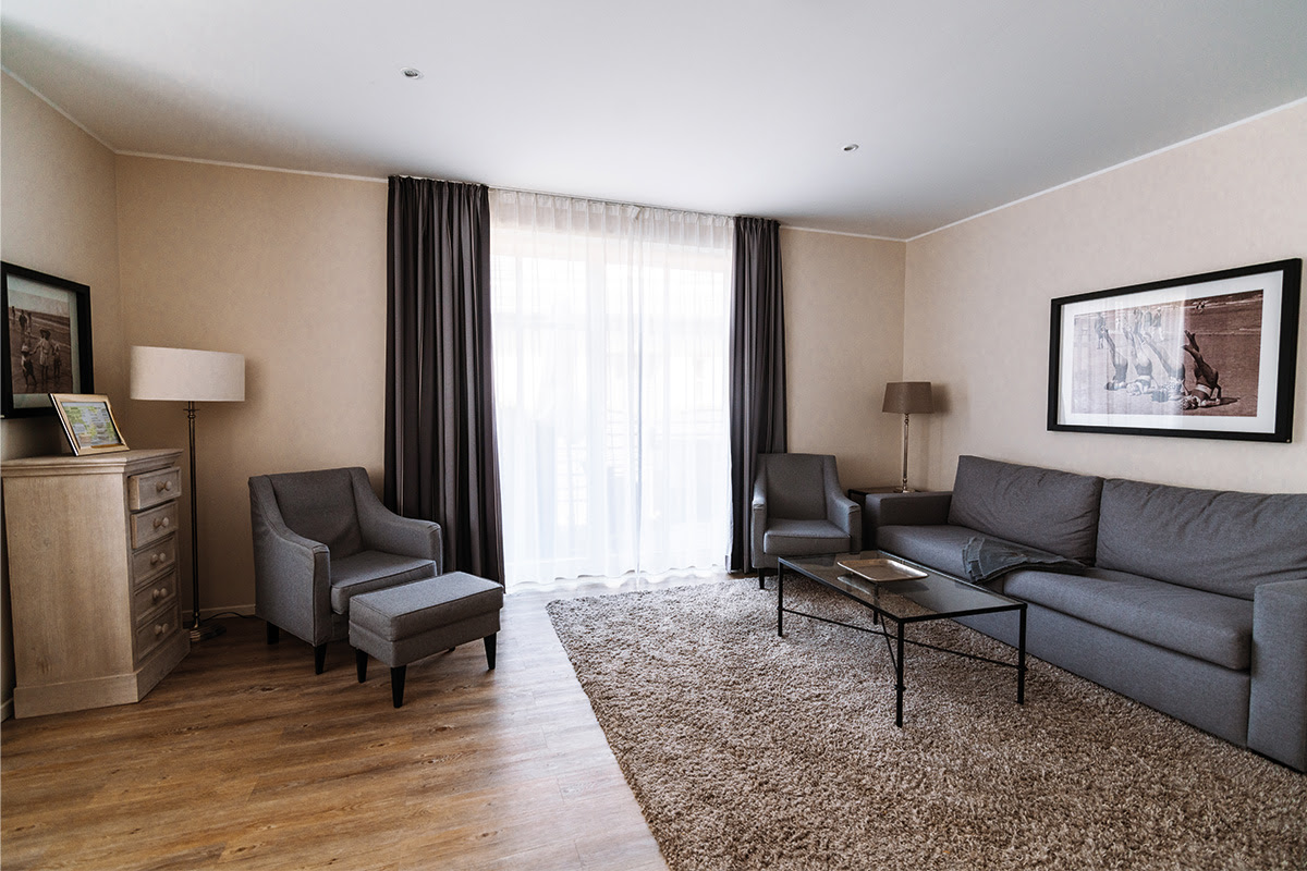 Comfortable living room with large window and sofa in the Strandmuschel vacation apartment in the Hotel Künstlerquartier Seezeichen.