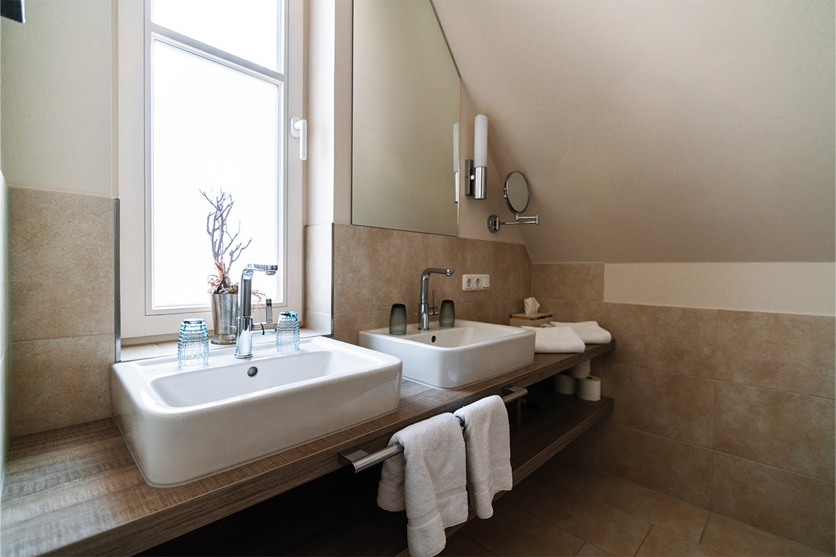 Elegantes Badezimmer mit Doppelwaschbecken und Tageslicht in der Ferienwohnung Strandnixe im Dünenpark Ahrenshoop.