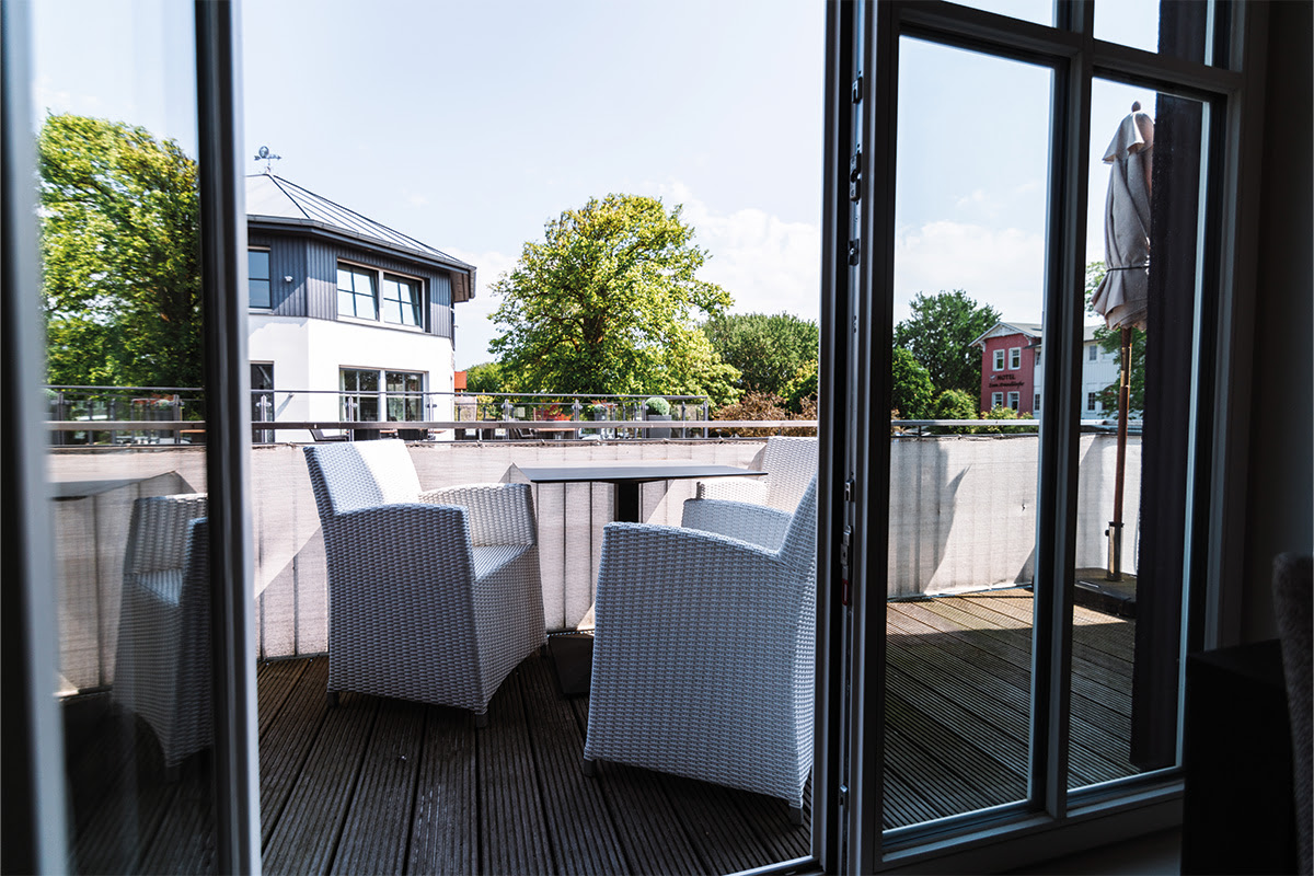Private balcony with rattan furniture of the Strandnixe vacation apartment in the dune park of the Künstlerquartier Seezeichen hotel.